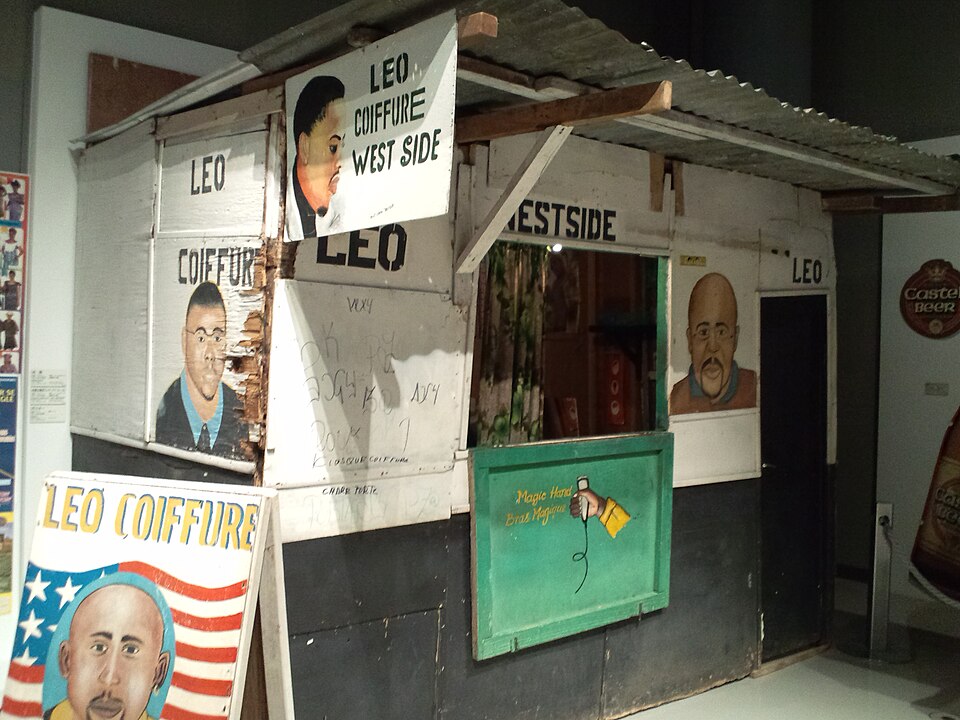 African Barbershop Sign — Sign of the LEO COIFFURE barbershop in Abidjan, Côte d'Ivoire (National Museum of Ethnology, collected 2005) — Wikimedia Commons / CC BY-SA 3.0 · © Yanajin33
